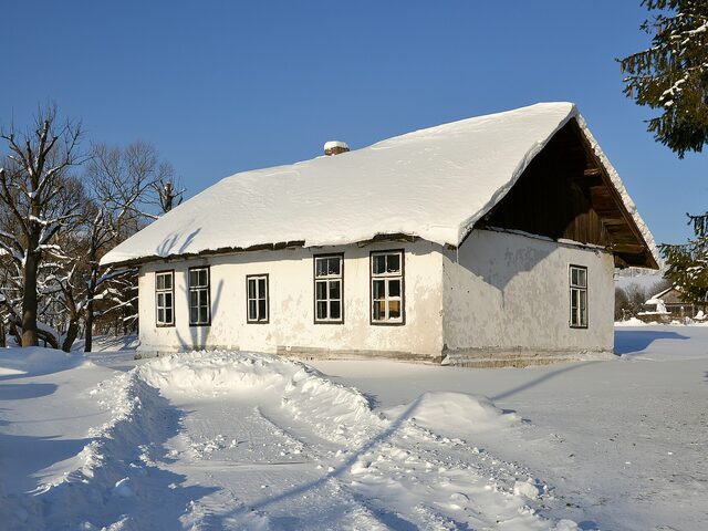 Maison dont la toiture est entièrement recouverte de neige, un hiver